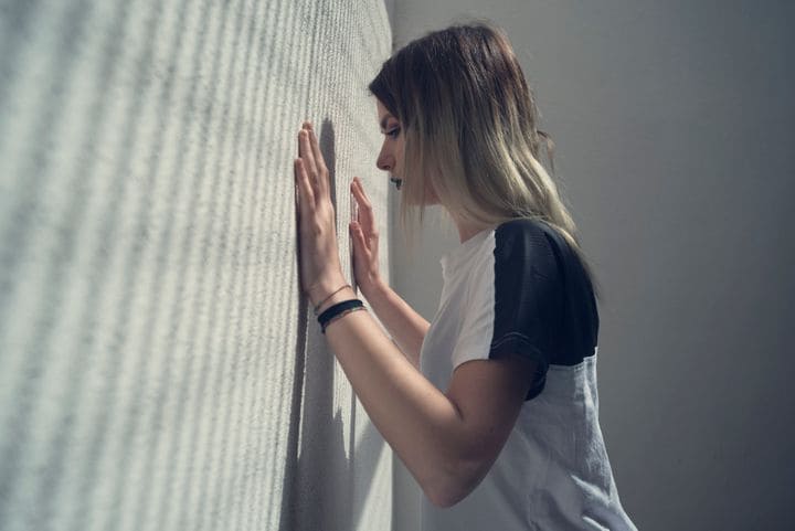 mujer apoyándose en la pared con las dos manos